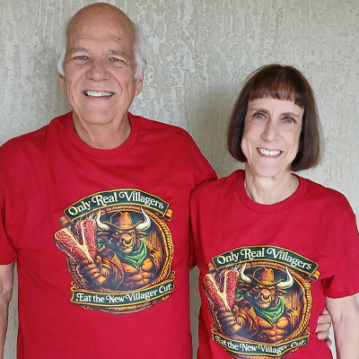 Smiling couple wearing matching Villages graphic shirts